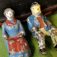 siddende metal kone og mand blåt tøj rødt forklæde gammelt legetøj